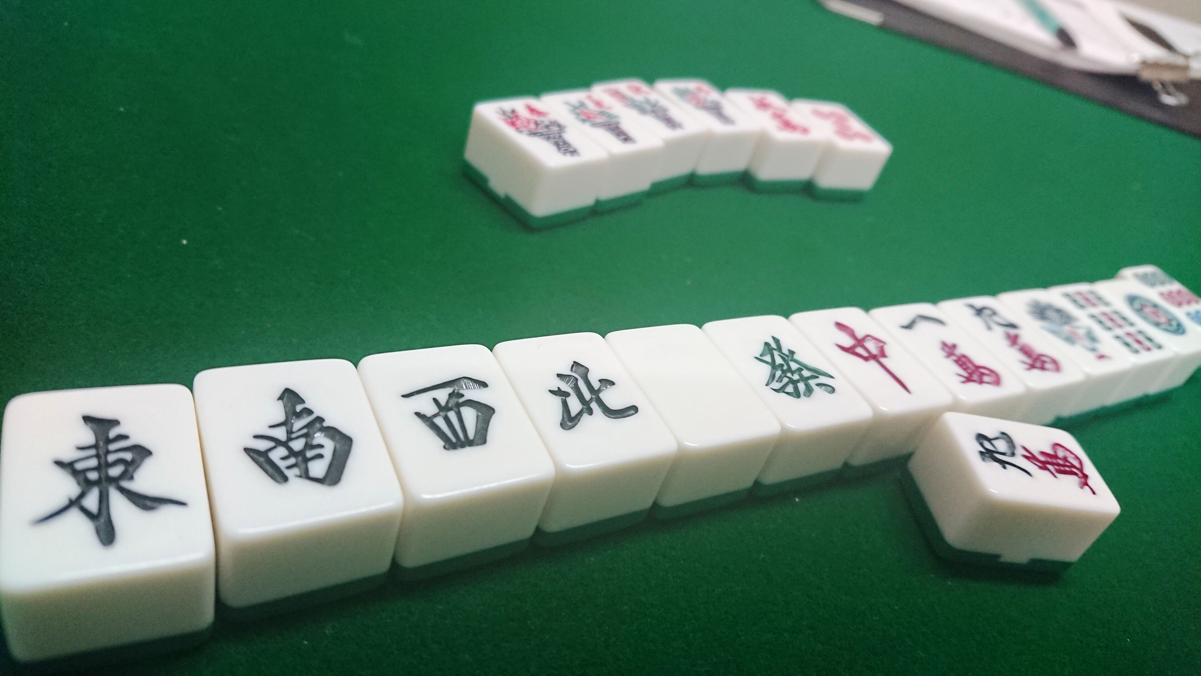 Fichas de mahjong dispuestas sobre una superficie verde.