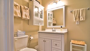 A bathroom with a toilet, a sink, a mirror, and a towel rack.