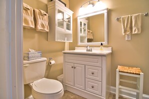 A bathroom with a toilet, a sink, a mirror, and a towel rack.
