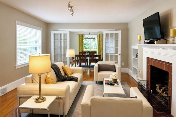A living room with a sofa, armchairs, a coffee table, a TV, and a fireplace.