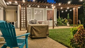 An outdoor patio area with a covered seating area, a table, and chairs.