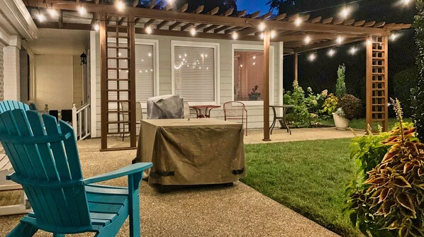 An outdoor patio area with a covered seating area, a table, and chairs.