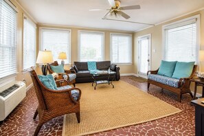 A living room with a ceiling fan, two sofas, a coffee table, and a patterned rug.