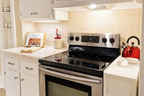 A modern kitchen with a stainless steel stove, a red kettle, and a cookbook on the counter.