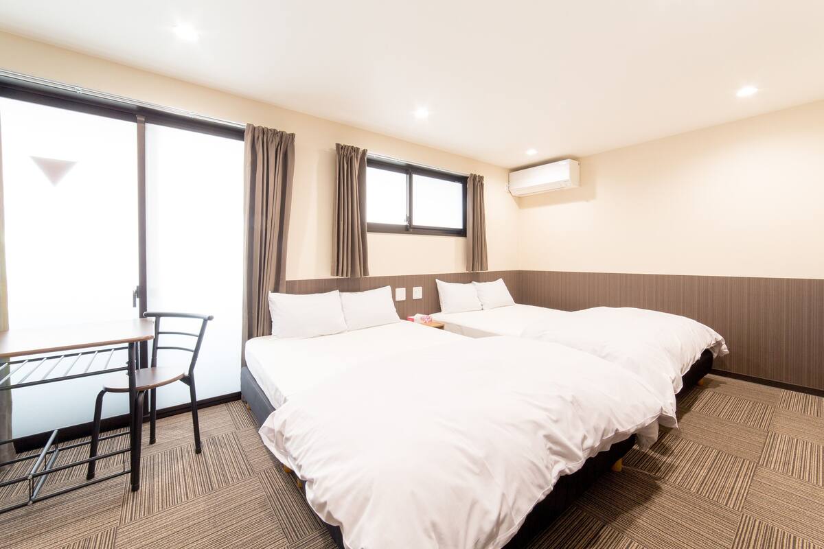 A hotel room with two beds, a desk, and a chair.