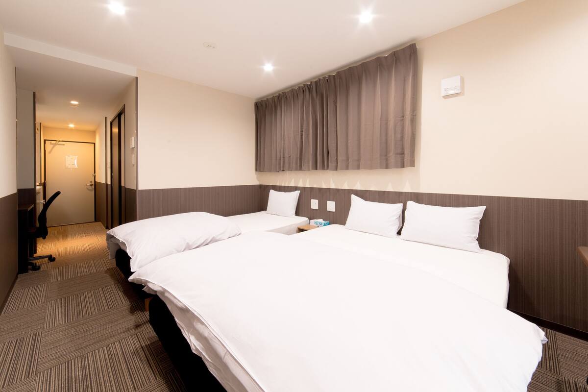 A hotel room with a large bed, a desk, and a chair.