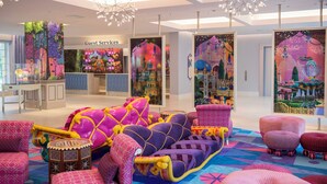 A vibrant lobby with colorful seating and artwork, a guest services desk, and a modern chandelier.