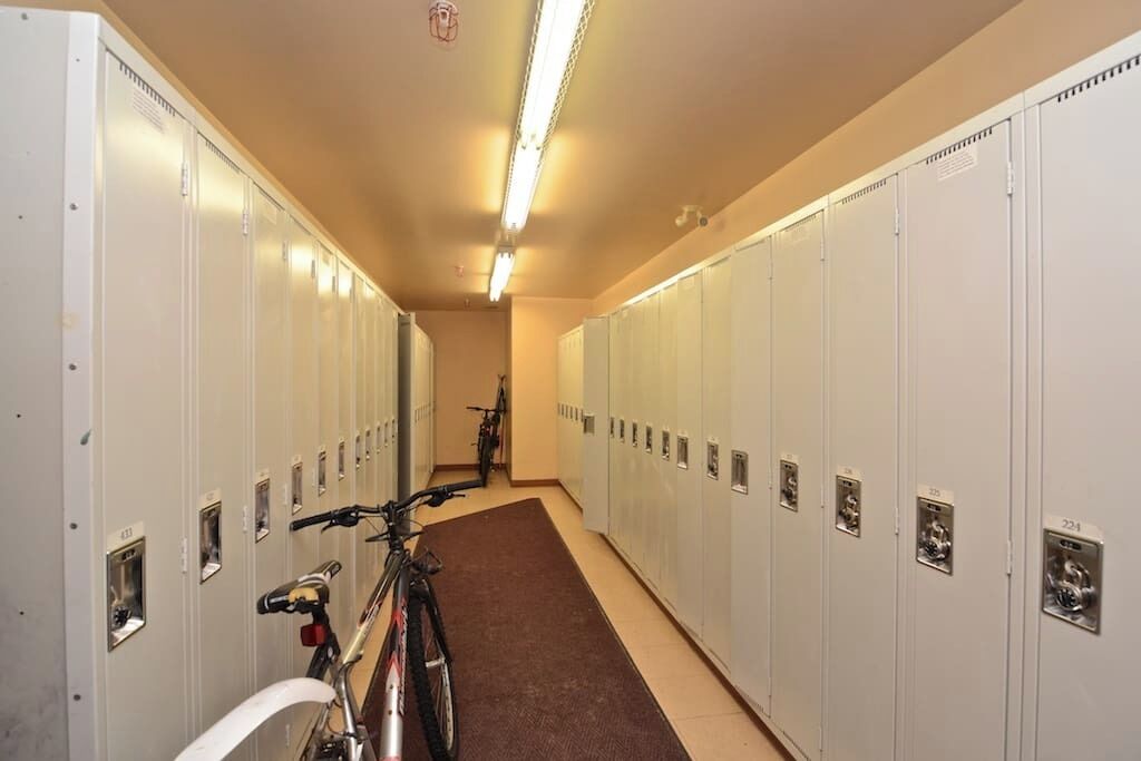 A locker room with multiple lockers, a bicycle, and a fluorescent light.
