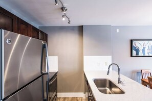 Una cocina moderna con un refrigerador de acero inoxidable, un lavamanos y una silla de madera.