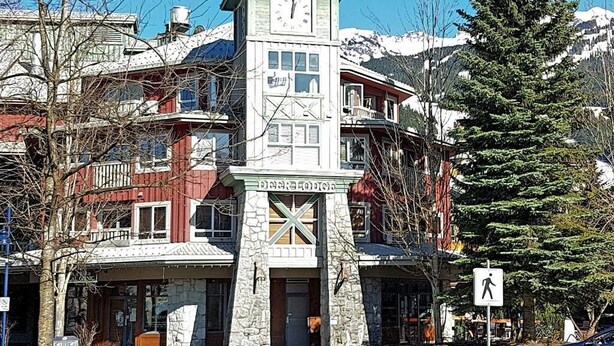 Un edificio con una torre de reloj, fachada de piedra y varios pisos.