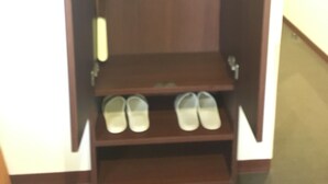 A wooden wardrobe with a hanging rod and shelves for shoes.