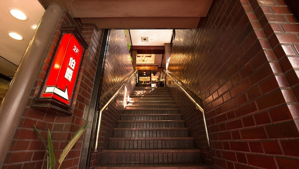 A staircase with a red sign, brick walls, and a ceiling with recessed lighting.
