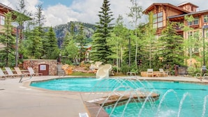 A pool with a water slide, lounge chairs, and a mountainous backdrop. - Pristine Ski Retreat, Slope Views in Solitude Village, 2 Bedroom, 2 Bath (Solitude)