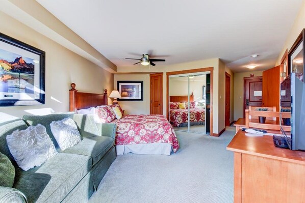 Ein Hotelzimmer mit Bett, Sofa, Schreibtisch und Deckenventilator.