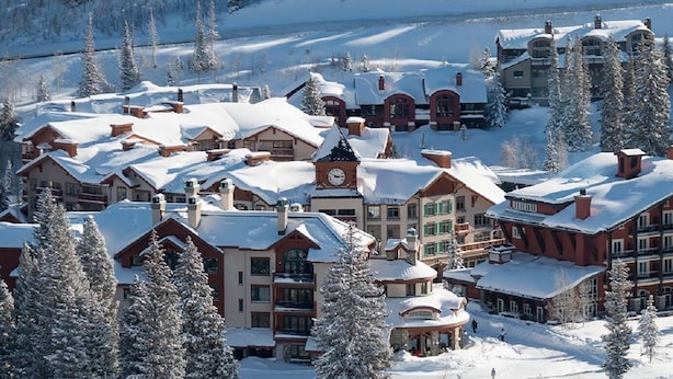 A snow-covered resort with multiple buildings, including a prominent lodge with a clock tower and a large red building with balconies. - Pristine Ski Retreat, Slope Views in Solitude Village, 2 Bedroom, 2 Bath (Solitude)