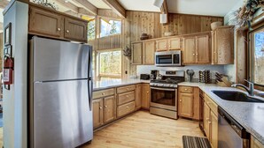 Et moderne køkken med træskabe, rustfrie stålapparater og et stort vindue der giver naturligt lys.