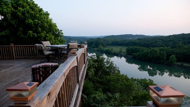 A wooden deck overlooking a river with a view of the surrounding greenery and hills.