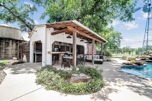 A covered outdoor seating area with a pool and patio furniture. - The Farmhouse: Modern Retreat in Fredericksburg (Fredericksburg)