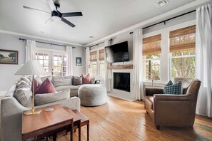 Una sala de estar con sofá, reposapiés, sillón, mesa de centro de madera y chimenea.