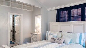 Een slaapkamer met een bed, een kaptafel, een spiegel en een raam met gordijnen.