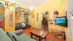 Un salon comprenant un canapé, une table basse et un téléviseur. Les murs sont décorés et il y a une fenêtre avec vue.