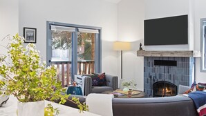 Ein modernes Wohnzimmer mit Kamin, einer Couch, einem Couchtisch und einem großen Fenster.
