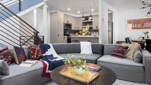 Ein modernes Wohnzimmer mit einem grauen Ecksofa, einem Couchtisch mit Tablett und einer Treppe.