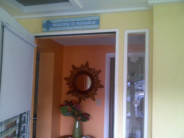 Una habitación con un espejo de rayos de sol, un letrero de bienvenida y un jarrón con flores.