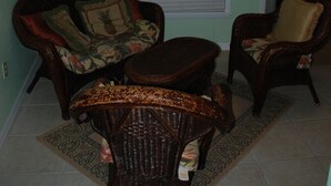 A room with two wicker chairs, a small table, and a door. - Old Florida Charm, quiet, close to beach and boat launch. (Englewood)