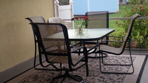 An outdoor patio with a table and chairs, a ceiling fan, and a view of a blue shed and greenery. - Old Florida Charm, quiet, close to beach and boat launch. (Englewood)