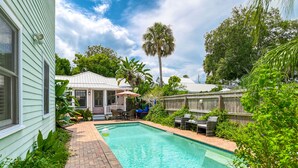 A backyard with a swimming pool, a covered patio, and lush greenery. - Historic Downtown Home with Private Heated Pool! Walk to Everything!  (St Augustine)