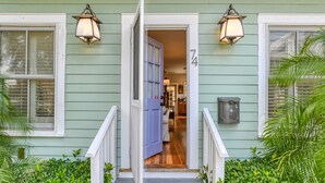 A green house with a blue door, white railings, and two wall-mounted lanterns. - Historic Downtown Home with Private Heated Pool! Walk to Everything!  (St Augustine)