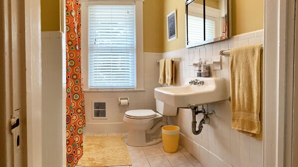 Een badkamer met toilet, wastafel en raam met zonwering.