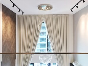 A modern hotel room with a large window, a chandelier, and a wooden accent wall. - Luxury Duplex at The Reach Titiwangsa (Kuala Lumpur)