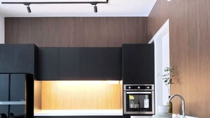A modern kitchen with a central island, black cabinetry, and a wooden accent wall.