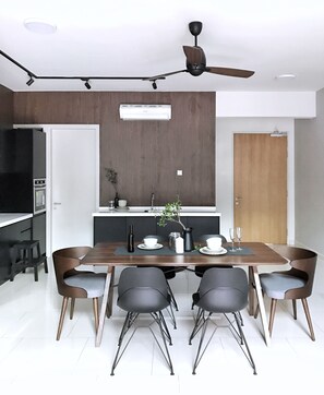 A modern dining area with a wooden table, black chairs, and a ceiling fan. - Luxury Duplex at The Reach Titiwangsa (Kuala Lumpur)