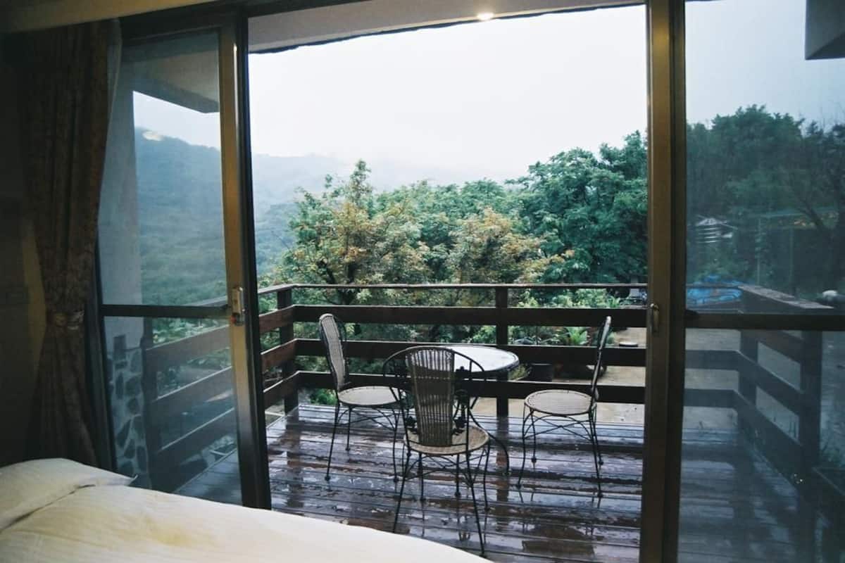 A room with a large window overlooking a balcony with a table and chairs.
