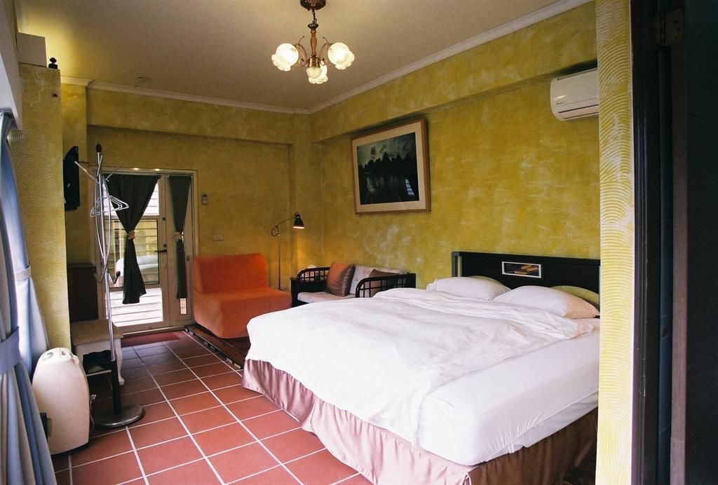 Une chambre d’hôtel avec un lit, une chaise, un bureau et un tableau au mur.