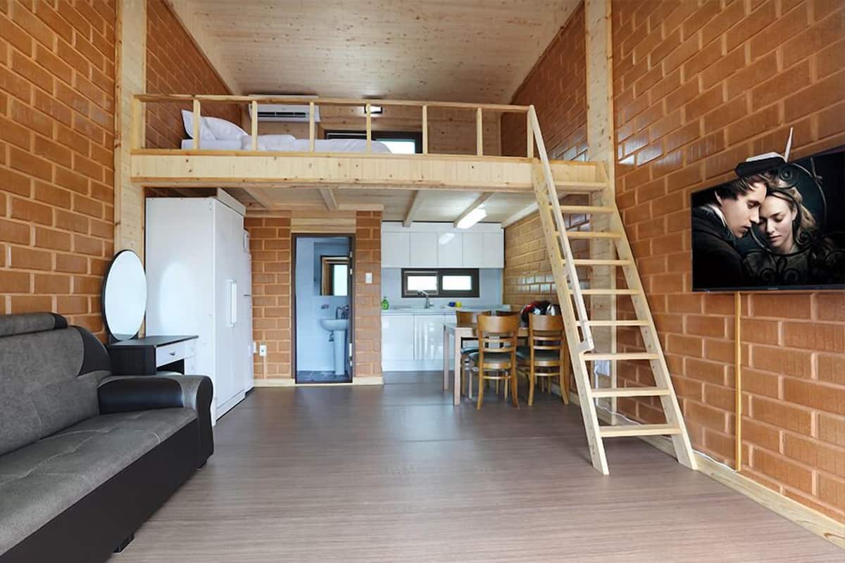 Ein Loft-Zimmer mit Stockbett, einer Couch, einer Küchenzeile und einem Esstisch.