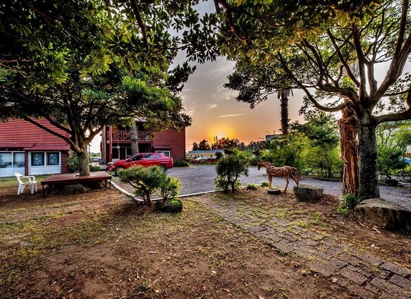 A residential area with a red car parked in front of a house, a horse statue, and a bench.