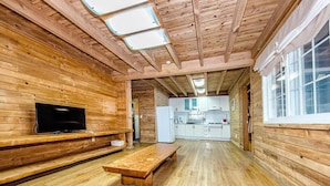 Ein Interieur einer Holzhütte mit Fernseher, einer hölzernen Bank und einer Küchenzeile.