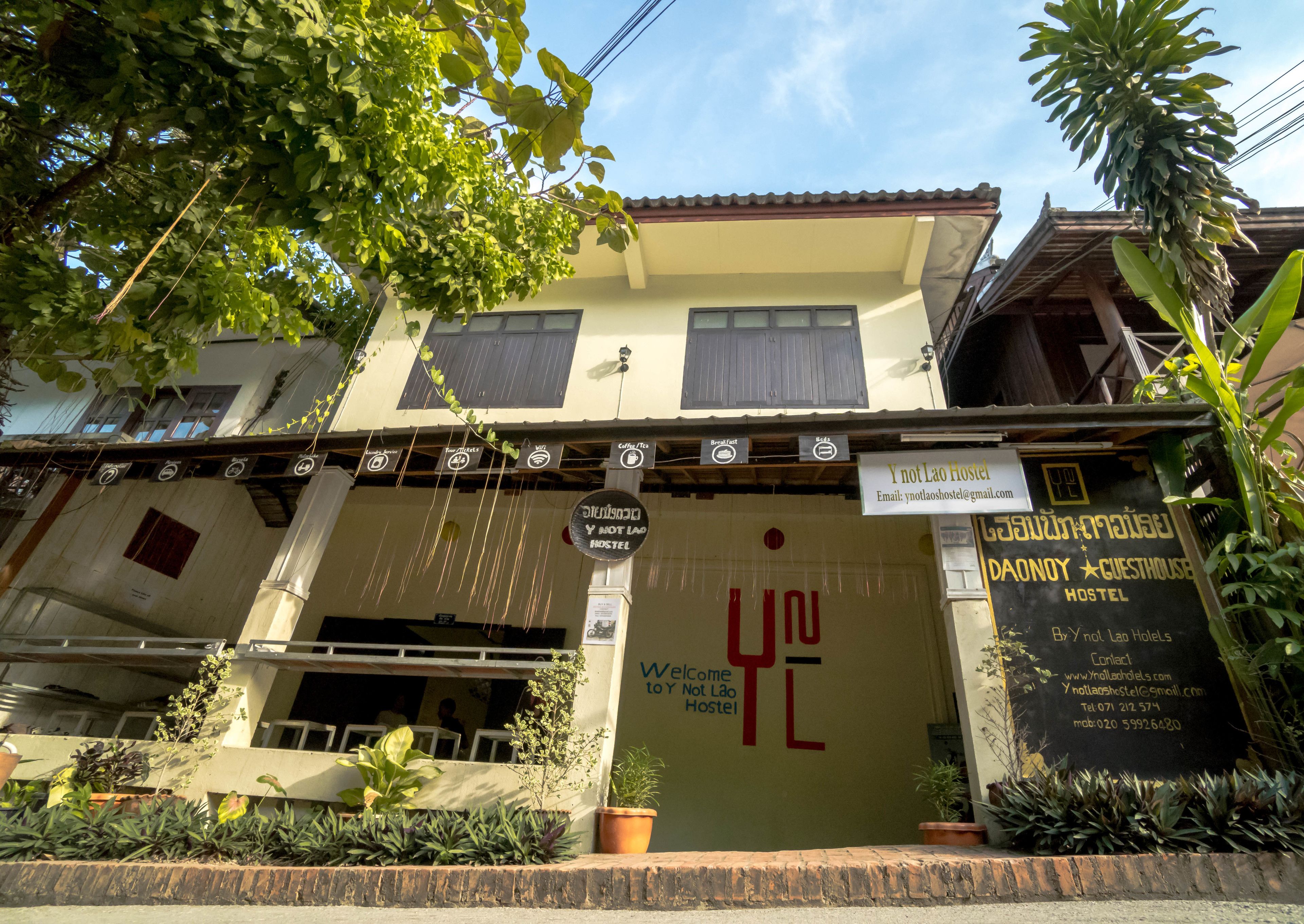 A hostel with a sign reading "Y not Lao Hostel" and "DAONOY GUESTHOUSE HOSTEL".