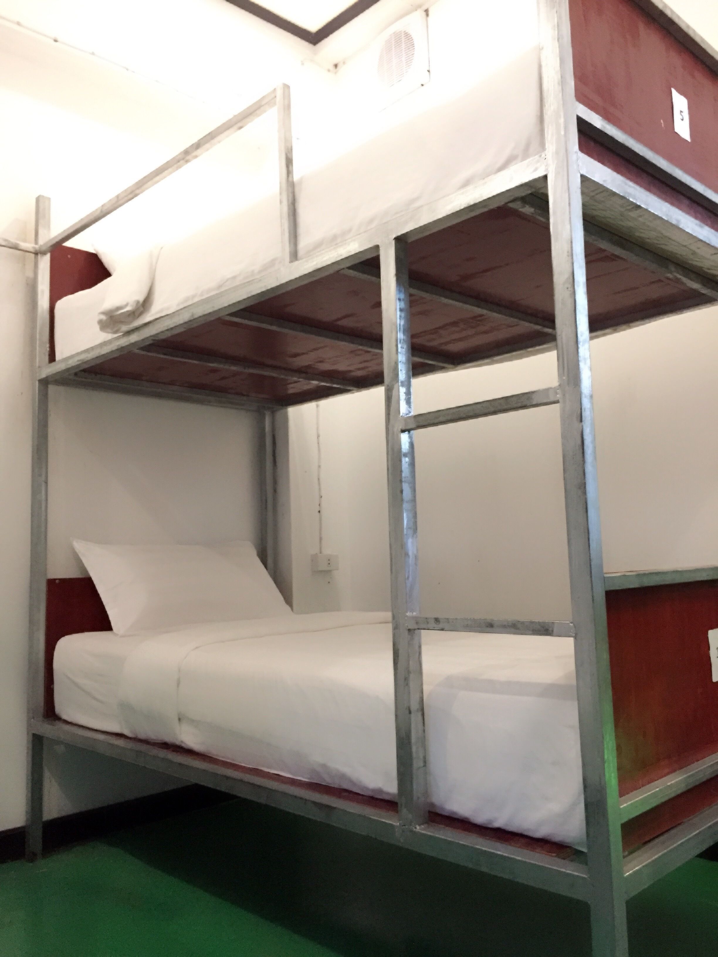 A bunk bed with metal railings and white bedding.