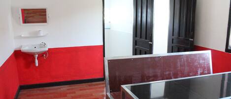 A room with a red and white color scheme, a white sink, a glass table, and a mirror on the wall.