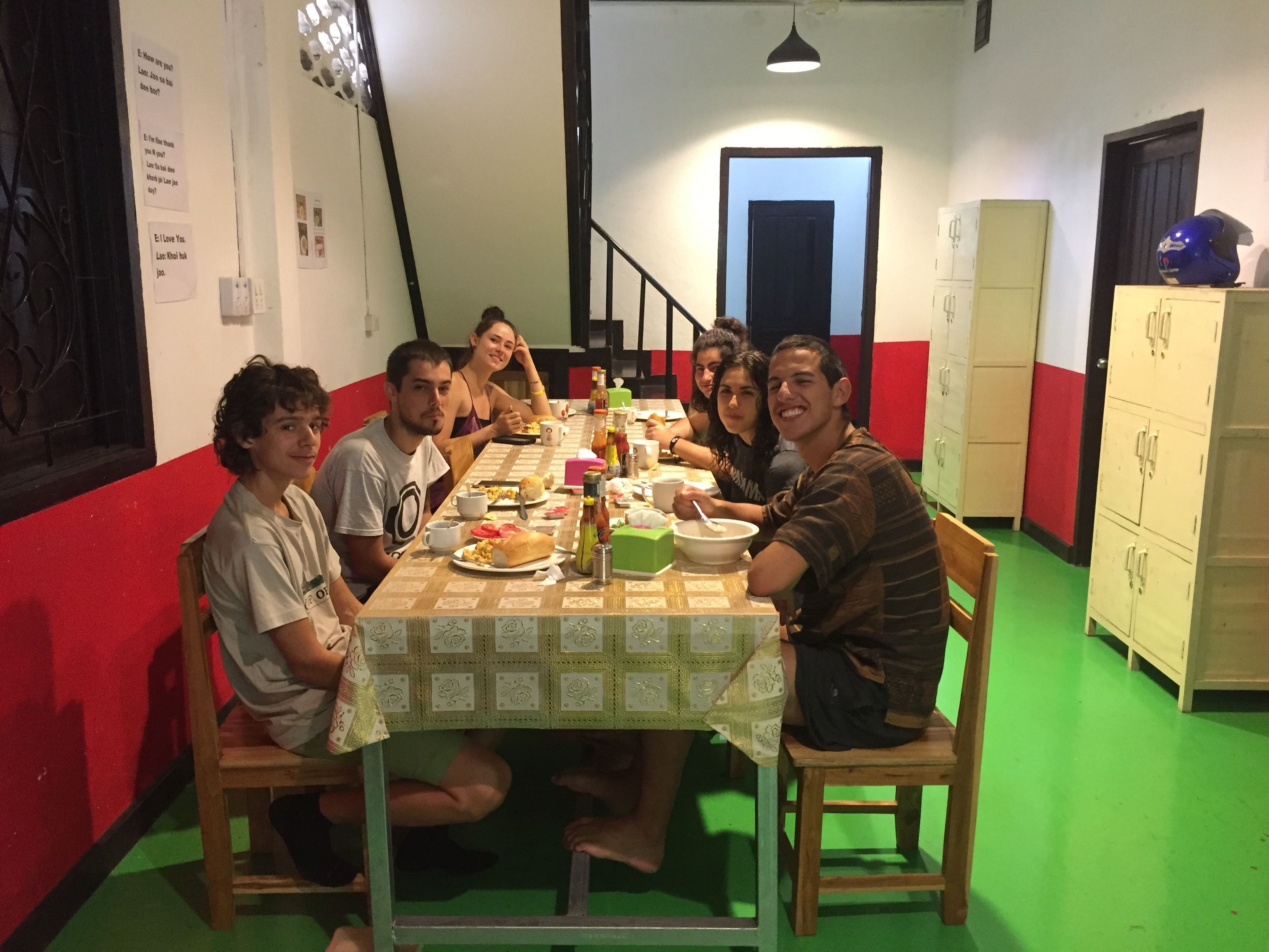Um grupo de pessoas jantando à mesa com toalha quadriculada em tons de verde e branco.
