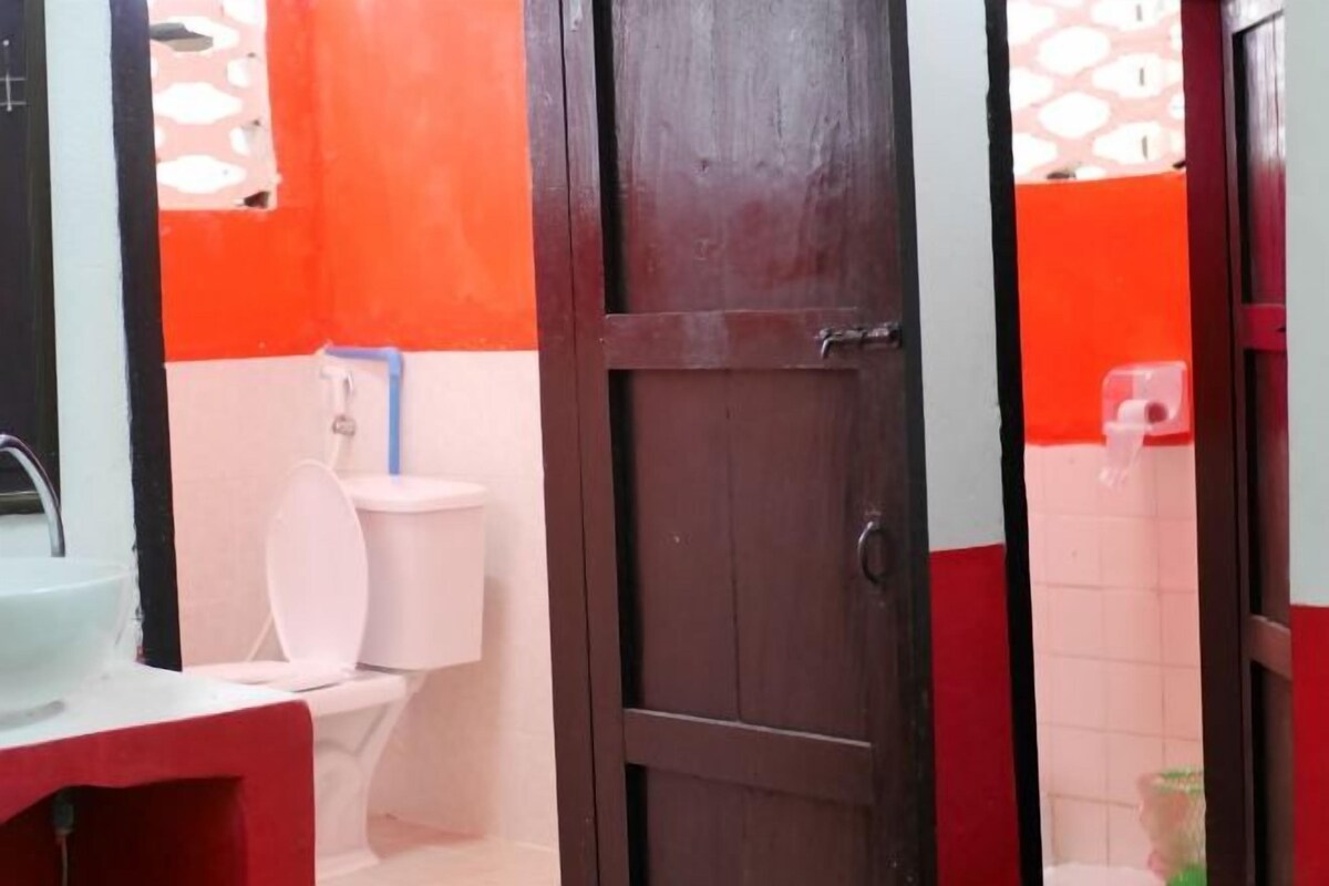 Un baño con inodoro, lavamanos y puerta de madera.