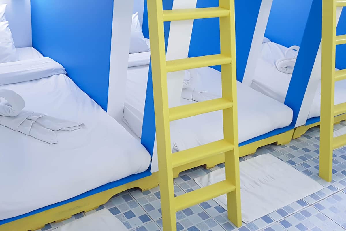 Una hilera de literas con ropa de cama blanca y paredes azules.