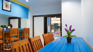 A hostel room with a blue table, wooden chairs, a potted plant, and a framed picture on the wall. - Hua Hin Night Market Hostel (Hua Hin)