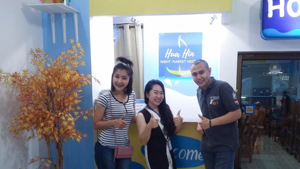 A reception area with a blue wall, a sign reading "Hua Hin Night Market Host," and a potted plant. - Hua Hin Night Market Hostel (Hua Hin)