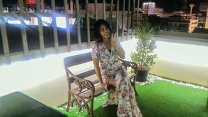 A person sitting on a bench with a potted plant beside them. - Hua Hin Night Market Hostel (Hua Hin)